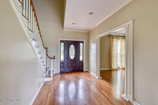 foyer with crown molding, light hardwood / wood-style floors, and ornate columns