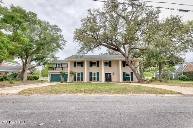 view of front of home with a garage, a balcony, and a front yard