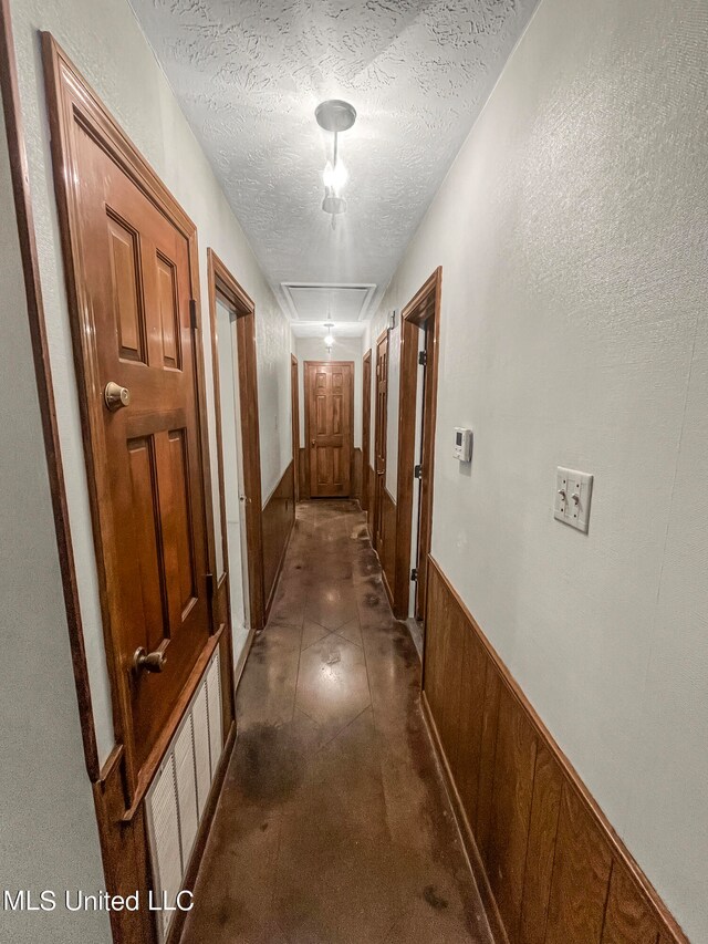 hall with wooden walls and a textured ceiling