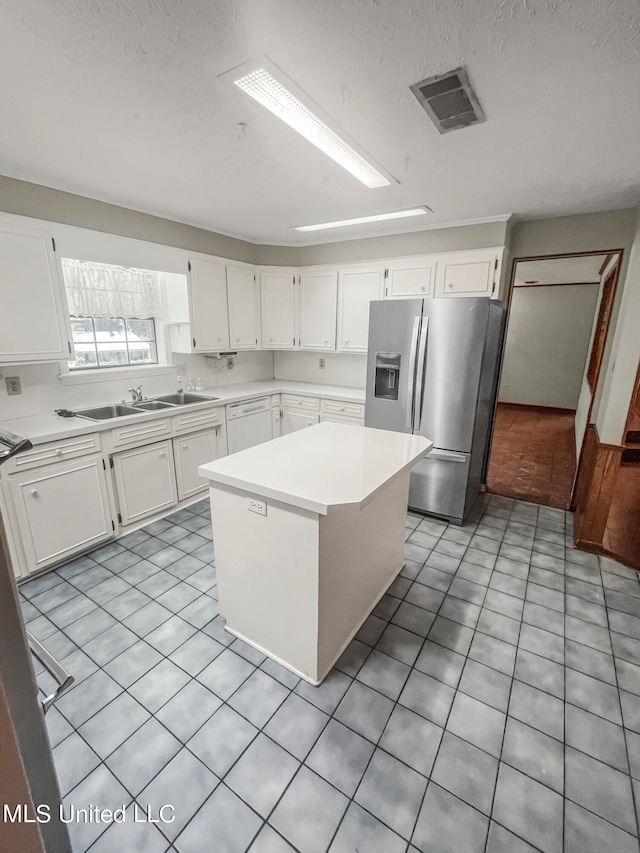 kitchen featuring stainless steel fridge, white cabinets, dishwasher, sink, and a center island