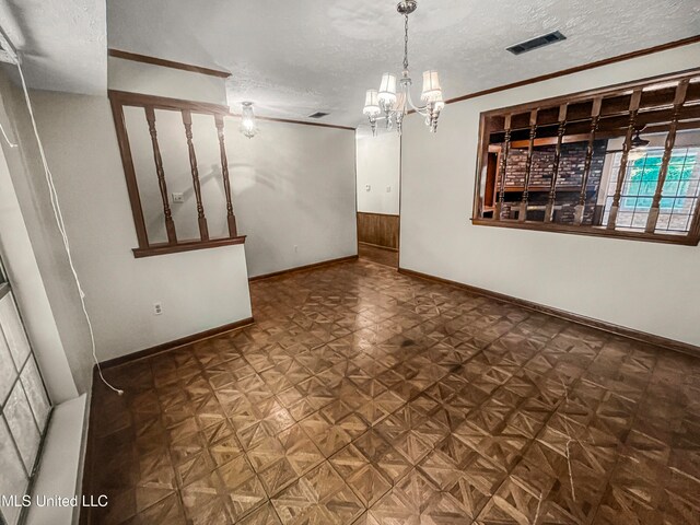 unfurnished dining area featuring dark parquet floors, a notable chandelier, a textured ceiling, and ornamental molding