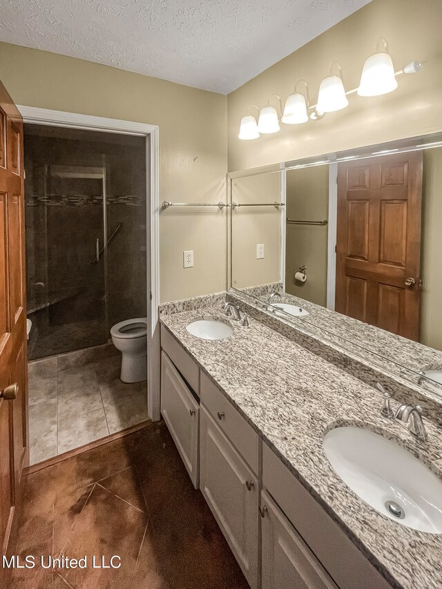 bathroom with tile patterned floors, toilet, vanity, a textured ceiling, and walk in shower