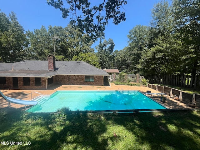 view of pool with a patio, a water slide, and a lawn