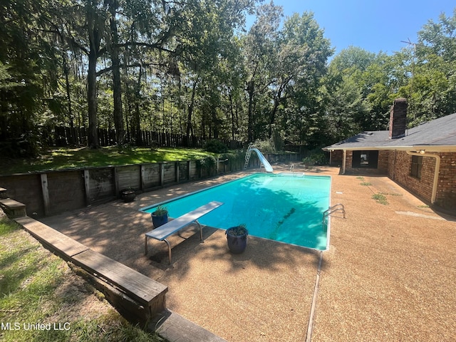 view of swimming pool with a patio, a water slide, and a diving board