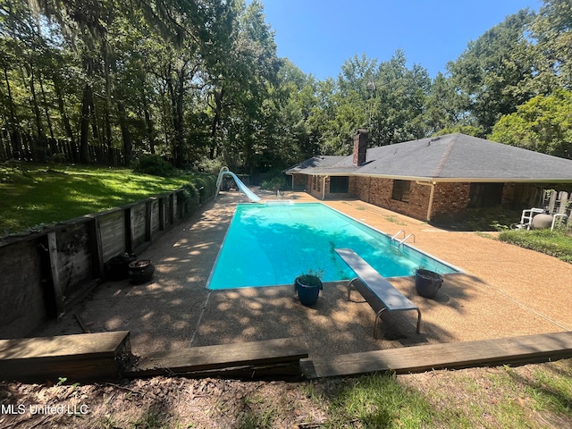 view of pool with a patio, a water slide, a diving board, and a yard