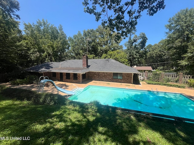 view of pool featuring a patio area, a water slide, and a yard