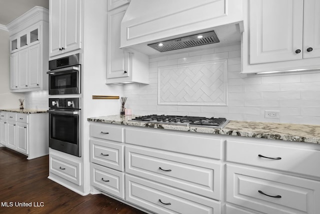 kitchen featuring light stone countertops, dark wood finished floors, custom exhaust hood, appliances with stainless steel finishes, and white cabinetry