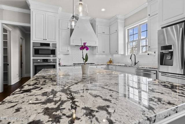 kitchen featuring premium range hood, stainless steel appliances, crown molding, and white cabinetry