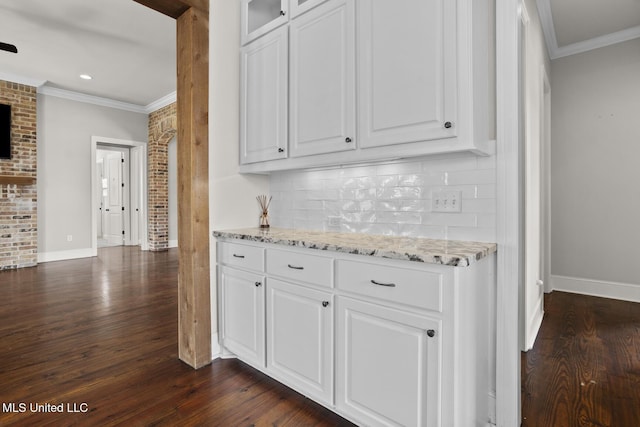 kitchen featuring light stone counters, backsplash, white cabinets, and crown molding