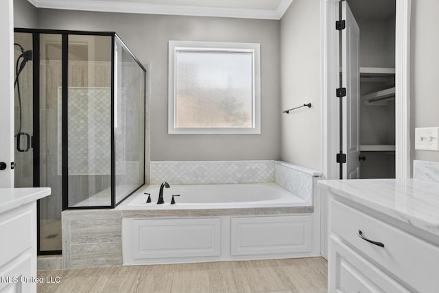 bathroom featuring vanity, a shower stall, a garden tub, and crown molding