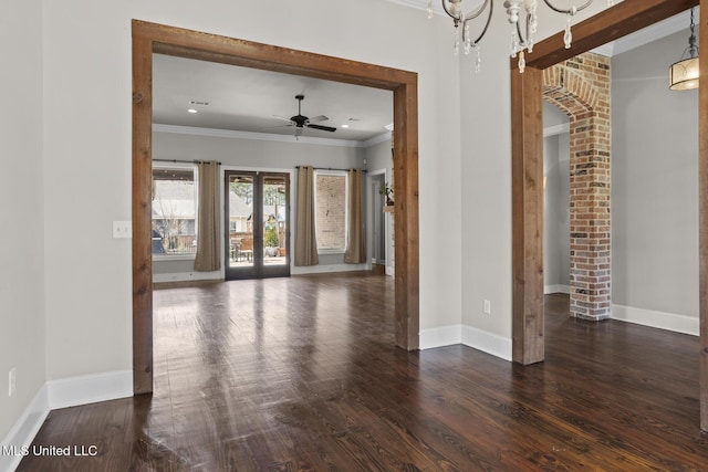 empty room featuring a ceiling fan, wood finished floors, baseboards, french doors, and crown molding