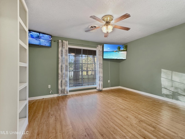 empty room with a textured ceiling, light wood-type flooring, and ceiling fan