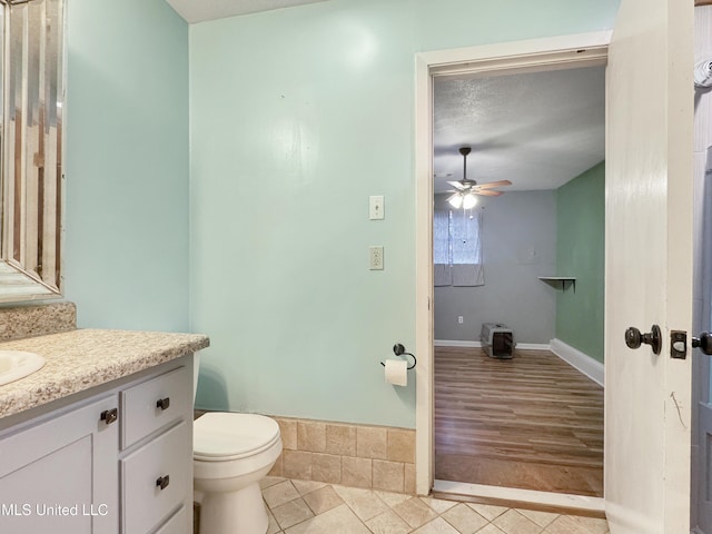 bathroom with a textured ceiling, vanity, ceiling fan, hardwood / wood-style flooring, and toilet