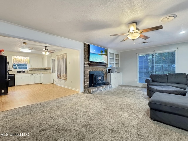 living room featuring a wood stove, a textured ceiling, light hardwood / wood-style flooring, and sink