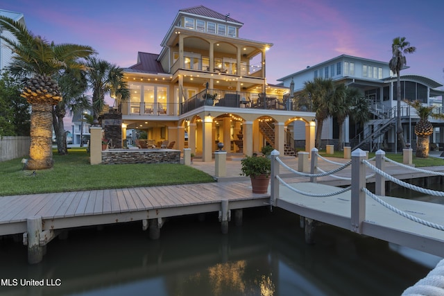 back of property at dusk with a balcony, a patio area, metal roof, stairs, and a standing seam roof