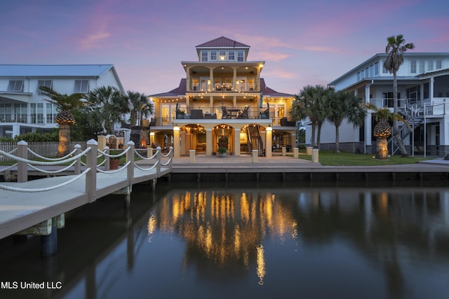 back of property featuring a water view, metal roof, a balcony, and a standing seam roof