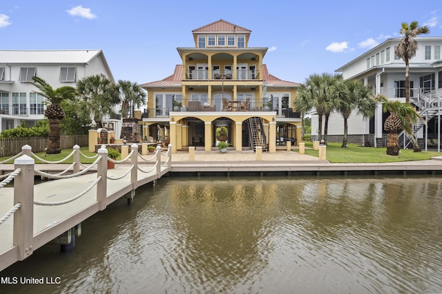 back of property featuring a water view, a balcony, stairway, and fence