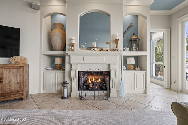 tiled living room featuring a warm lit fireplace, built in shelves, and ornamental molding