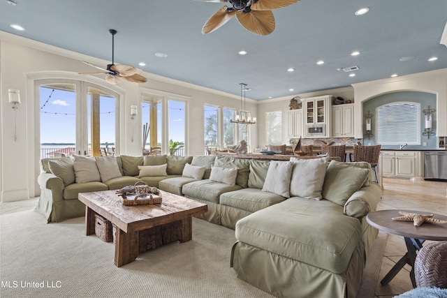 living room featuring ceiling fan, ornamental molding, recessed lighting, a chandelier, and arched walkways