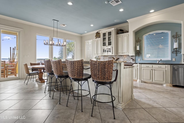 kitchen with stainless steel dishwasher, crown molding, a breakfast bar, recessed lighting, and glass insert cabinets