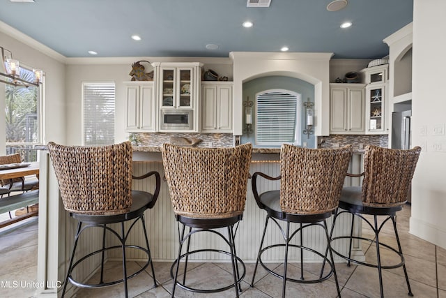 kitchen featuring backsplash, appliances with stainless steel finishes, recessed lighting, crown molding, and a kitchen bar