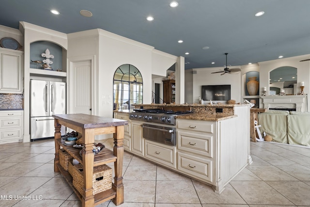 kitchen with appliances with stainless steel finishes, cream cabinetry, a warming drawer, open floor plan, and ceiling fan