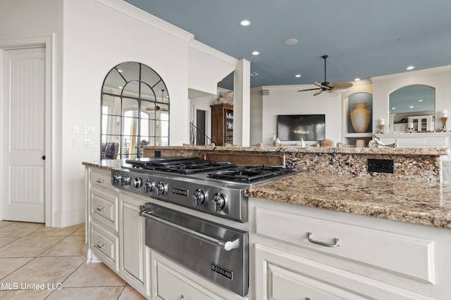 kitchen with a warming drawer, stainless steel gas stovetop, a ceiling fan, light stone counters, and light tile patterned floors