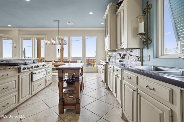 kitchen featuring cream cabinetry, stainless steel gas cooktop, a warming drawer, a sink, and a chandelier