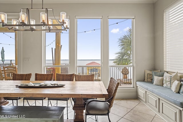 dining space featuring a chandelier, light tile patterned flooring, plenty of natural light, and a water view