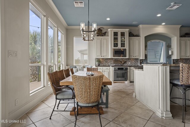 dining room with a chandelier, crown molding, light tile patterned floors, and recessed lighting