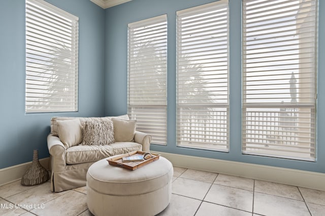living area with plenty of natural light, baseboards, tile patterned flooring, and crown molding