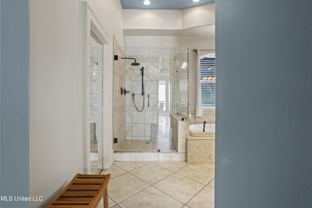 bathroom with a stall shower, tile patterned flooring, and a bath