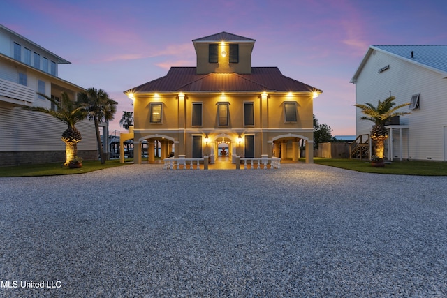 view of front of house featuring driveway, metal roof, covered porch, and stucco siding