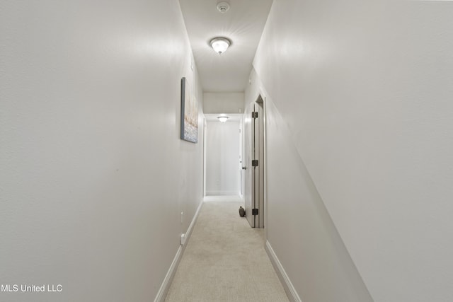 corridor featuring light colored carpet and baseboards
