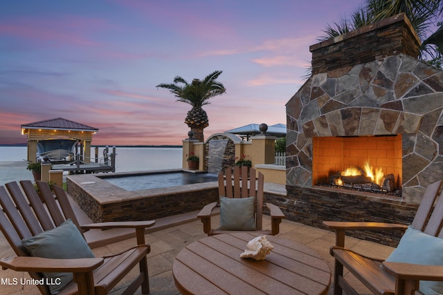 view of patio / terrace with an outdoor stone fireplace and a water view