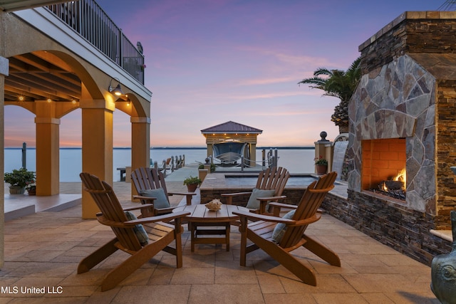 view of patio featuring an outdoor stone fireplace and a water view