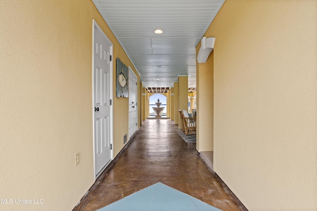 hallway featuring concrete flooring and baseboards