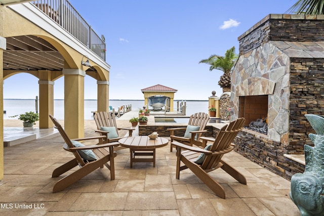 view of patio / terrace featuring an outdoor stone fireplace and a water view
