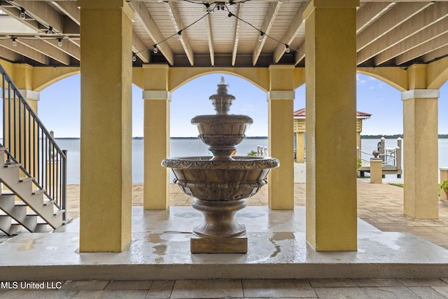 view of patio with stairs and a water view