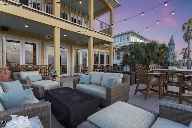 patio terrace at dusk featuring a balcony, french doors, outdoor lounge area, and outdoor dining space