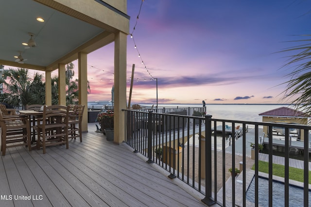 deck at dusk featuring a water view