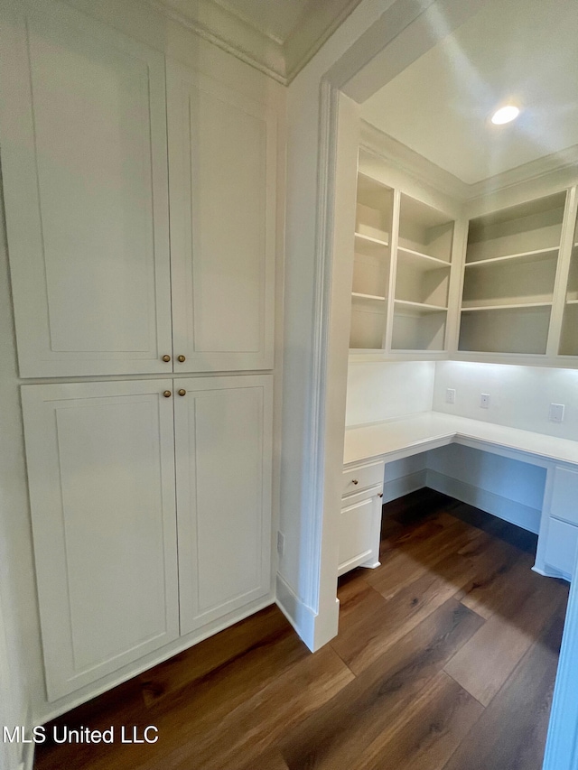 unfurnished office featuring dark hardwood / wood-style flooring and built in desk