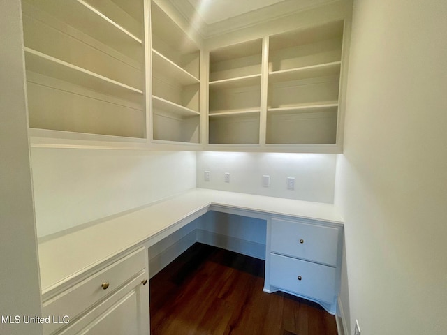 unfurnished office featuring built in desk and dark wood-type flooring