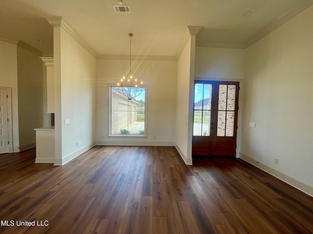 unfurnished dining area featuring an inviting chandelier, dark hardwood / wood-style flooring, crown molding, and french doors