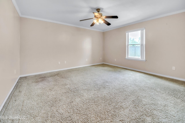 carpeted empty room featuring a ceiling fan, baseboards, and crown molding