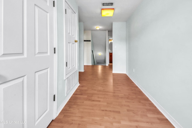 hallway featuring light wood-style floors, visible vents, and baseboards