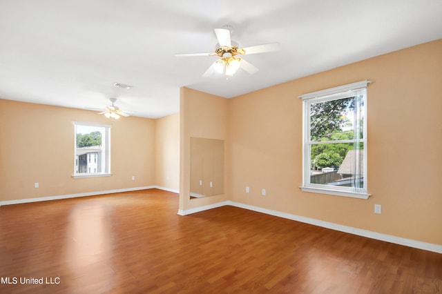 empty room featuring visible vents, ceiling fan, baseboards, and wood finished floors