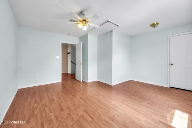 spare room with visible vents, light wood finished floors, attic access, and baseboards