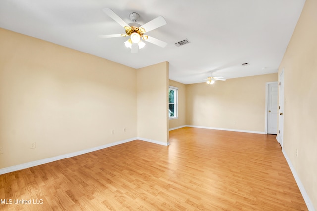 empty room with ceiling fan, light wood-style flooring, visible vents, and baseboards