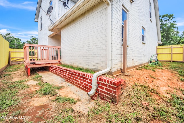 view of side of property featuring a fenced backyard, a wooden deck, and brick siding